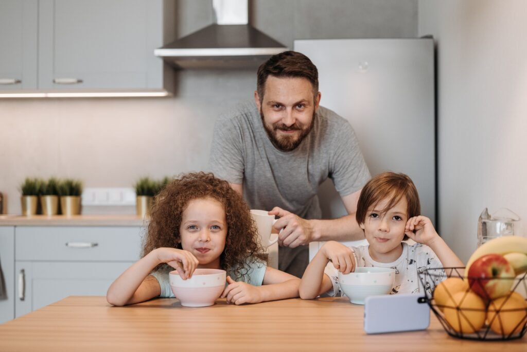 Father and children enjoying breakfast together in a cozy kitchen setting.